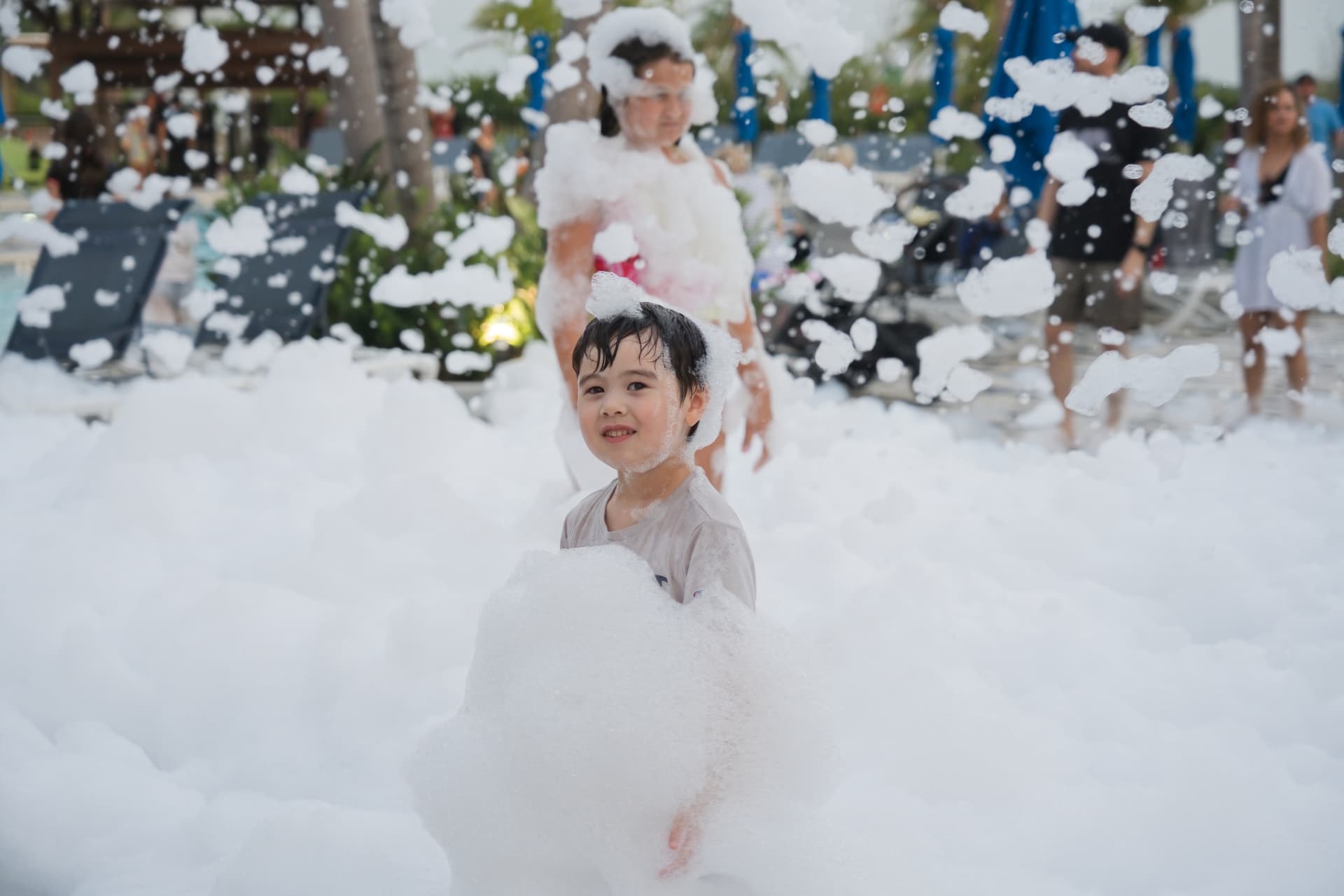 Smiling child holding a large handful of foam at a foam party
