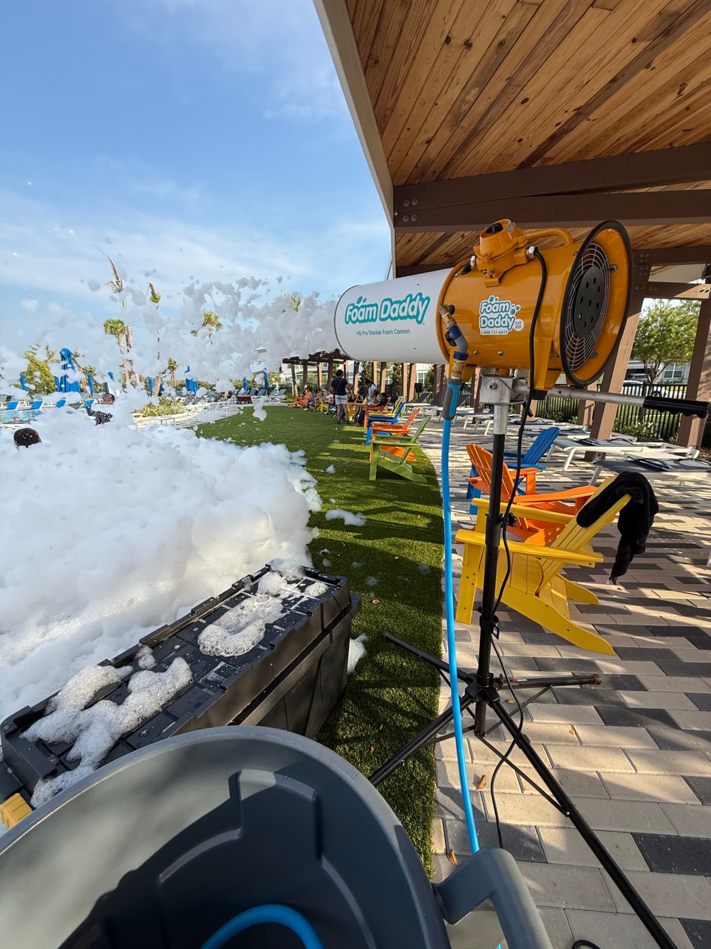 Foam Daddy HD Pro Stacker on a tripod with a garden hose feed, throwing foam across a lawn at a real event
