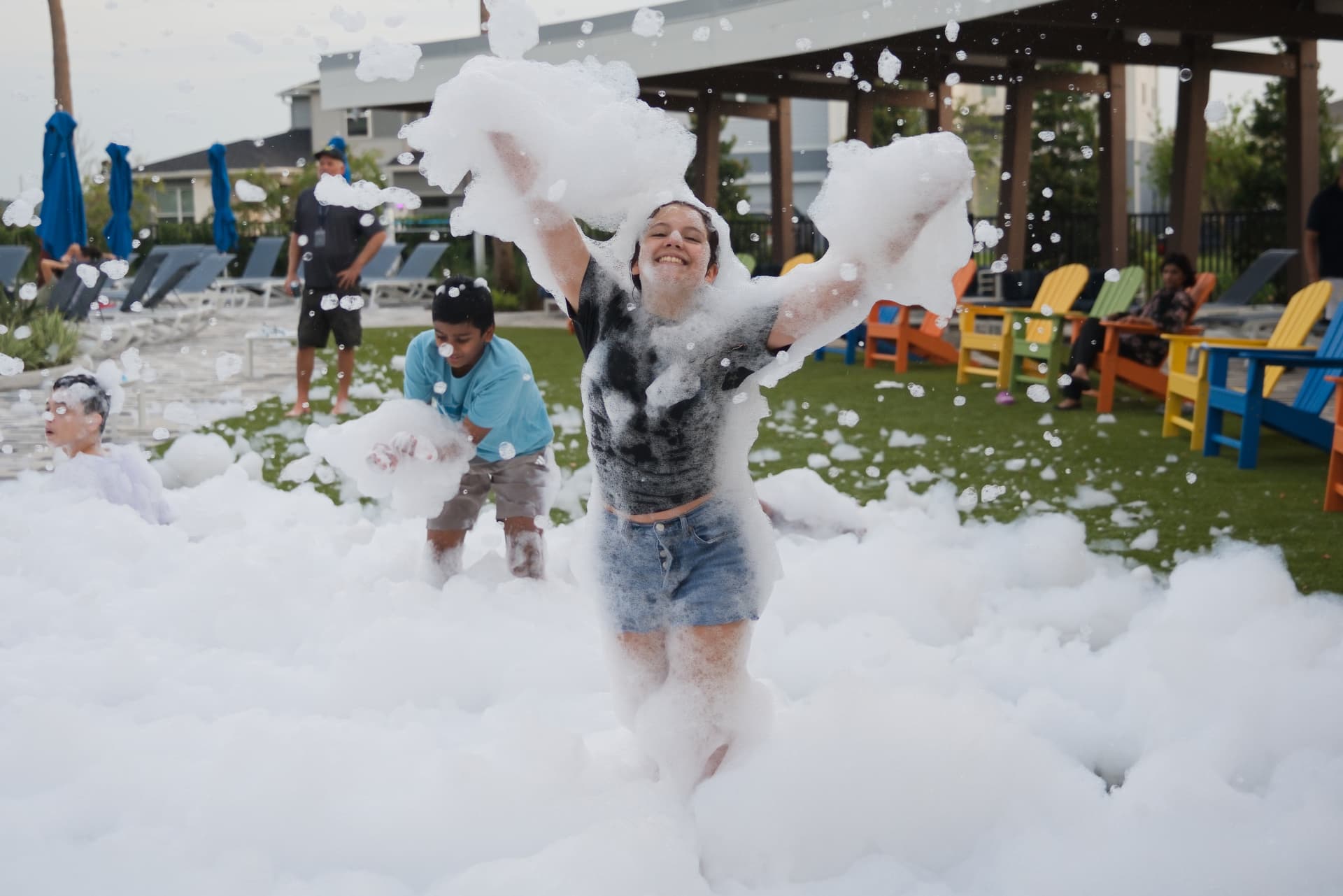 Teen throwing two armfuls of foam in the air at a foam party