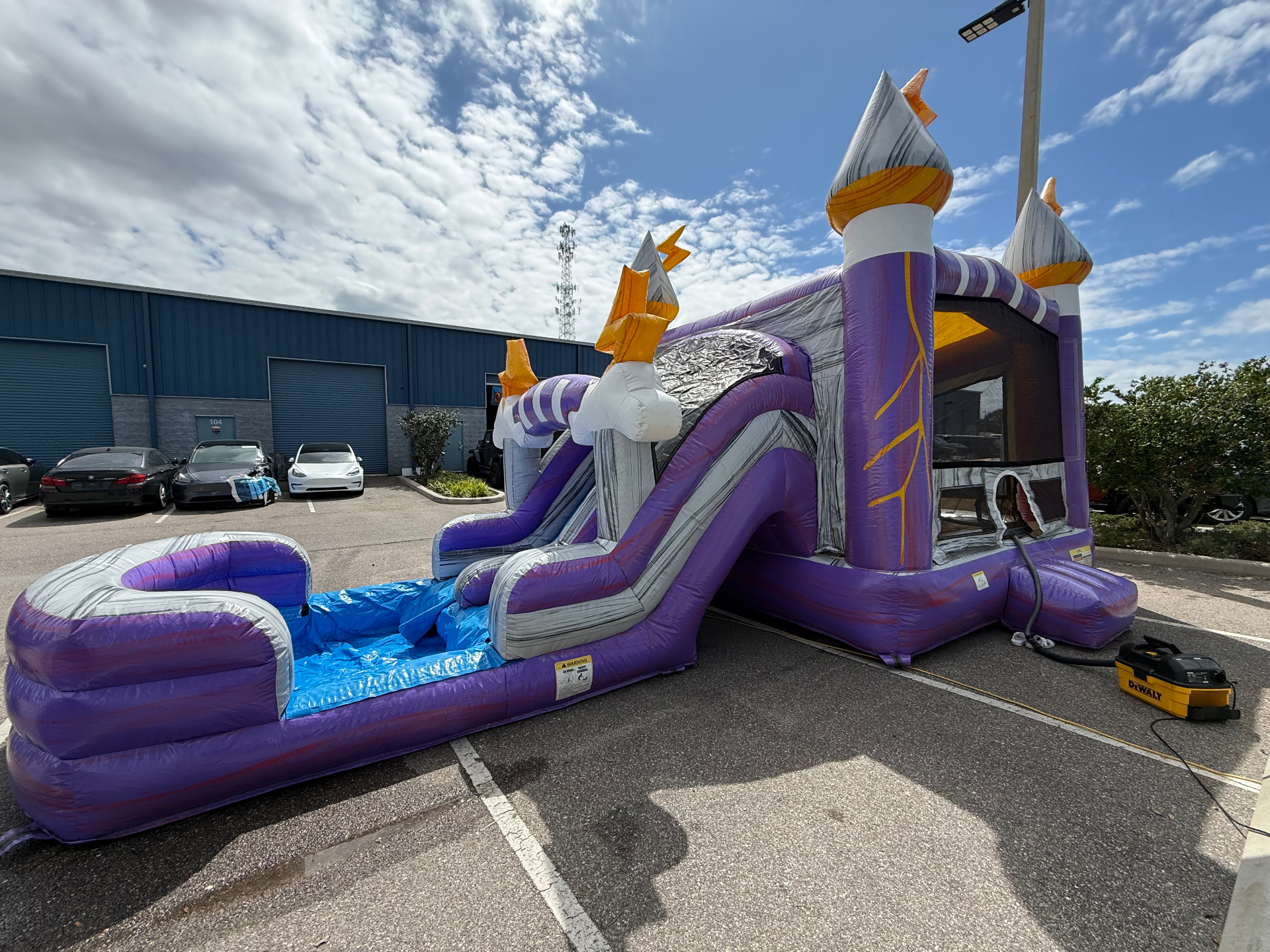 Purple and silver bounce house combo with water slide fully inflated outside the warehouse for a deep clean and inspection day.