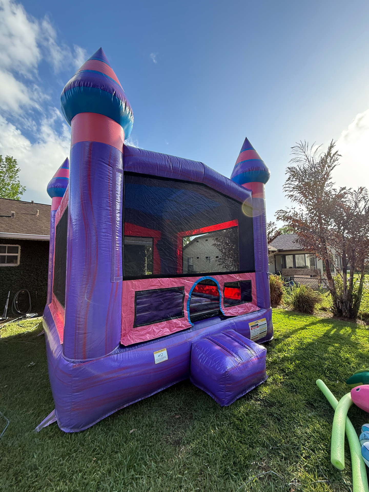 Purple and pink princess castle bounce house in a backyard